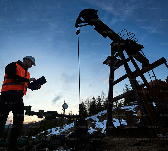 A worker in front of an oil pumpjack.